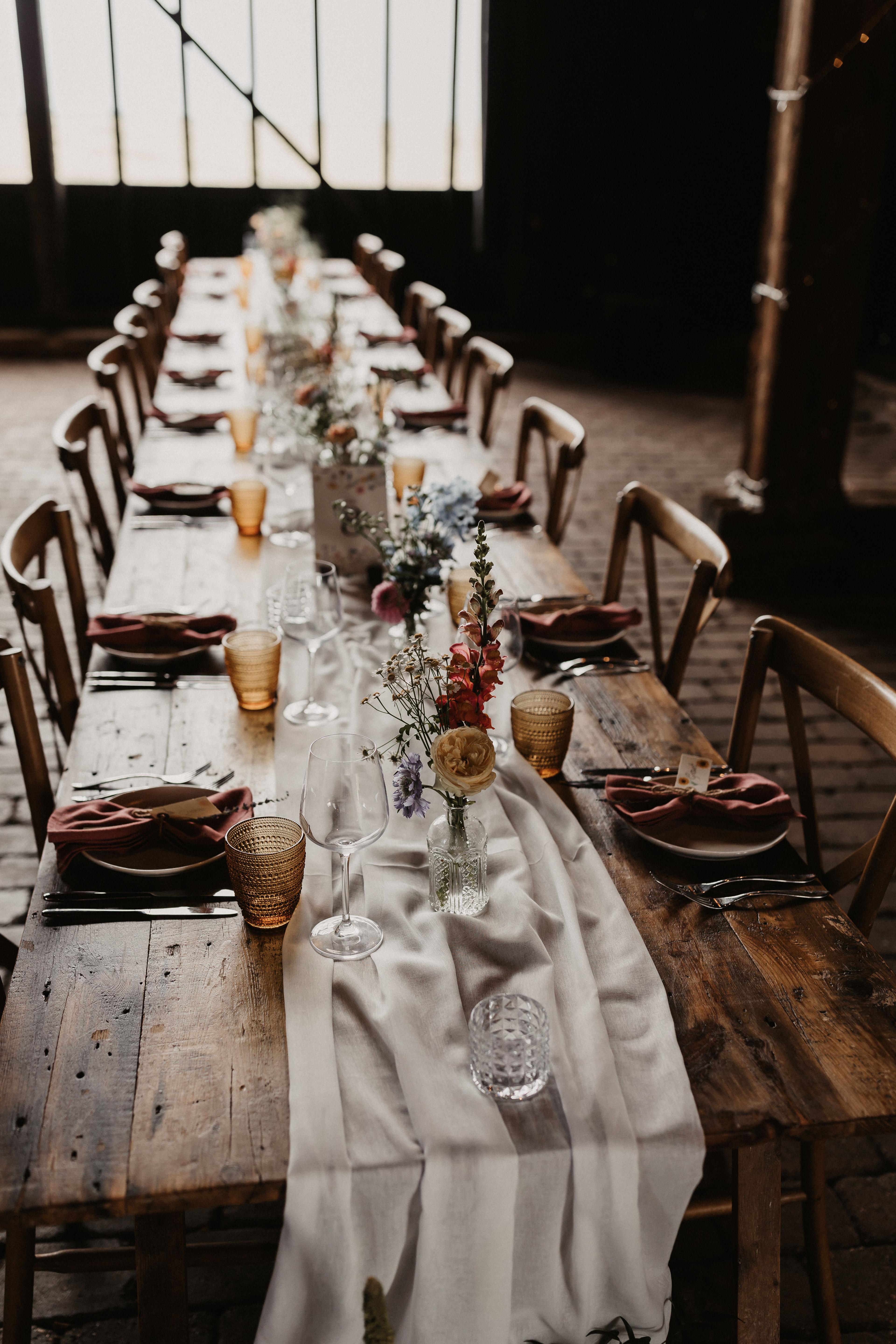 A long wooden table softly styled for a summer wedding in the Elmley Nature Reserve barn